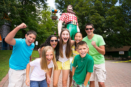 An image of a group of people, excited and smiling, in front of the Paul Bunyan statue with a balloon from the Sky Ride in the background.