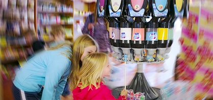 Image that is blurred on the sides but you can clearly tell its two girls in the candy shop looking at all the candy options.