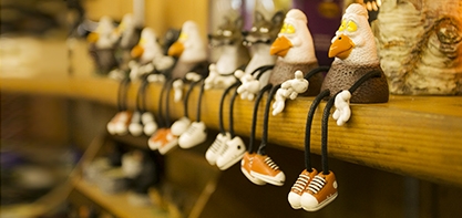 Image of souvenirs at the Woodsy souvenir shop. Little trinkets sitting one a shelf with their legs dangling off.