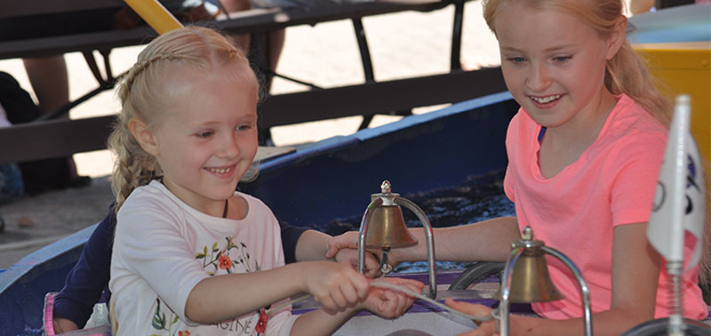 image of two little girls smiling on a ride.