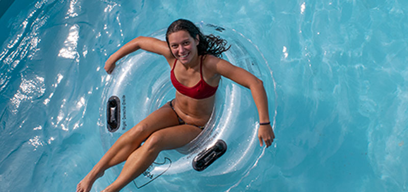 An image of a woman in a clear inner tube with black handles. She's in a blue pool.