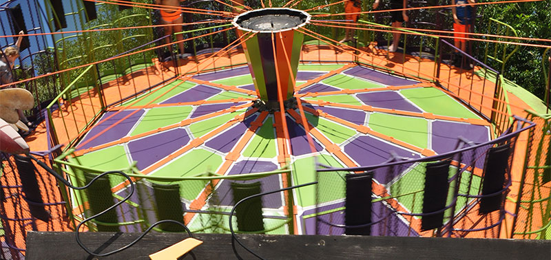 An image of a ride full of green, purple and orange. Spinning people around on a tilt called the Round-Up.