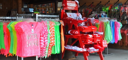 image of the Tiki Tim's Longboard Surf Shop. Image off different colors shirts on display along with lifeguard gear available for guests to buy.