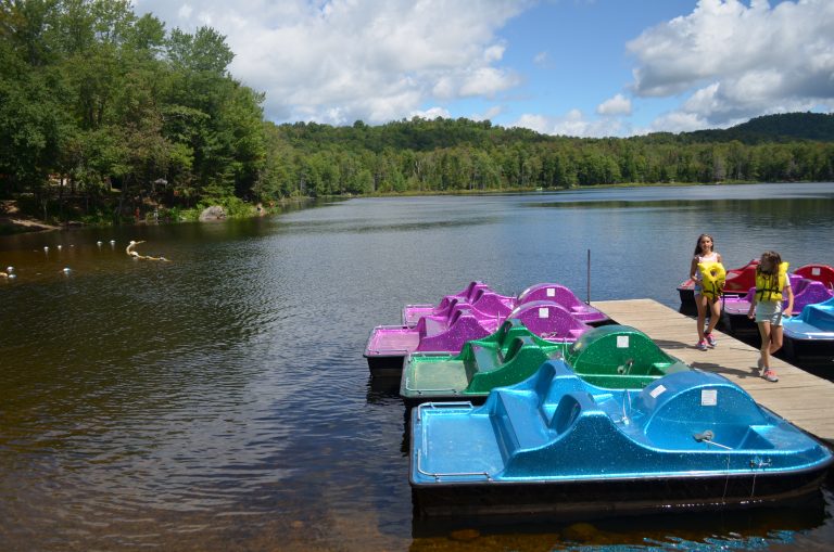 Photo showing Lake Serene at Old Forge Camping resort. Two young girls walking n the dock with the paddle boards attached the dock.