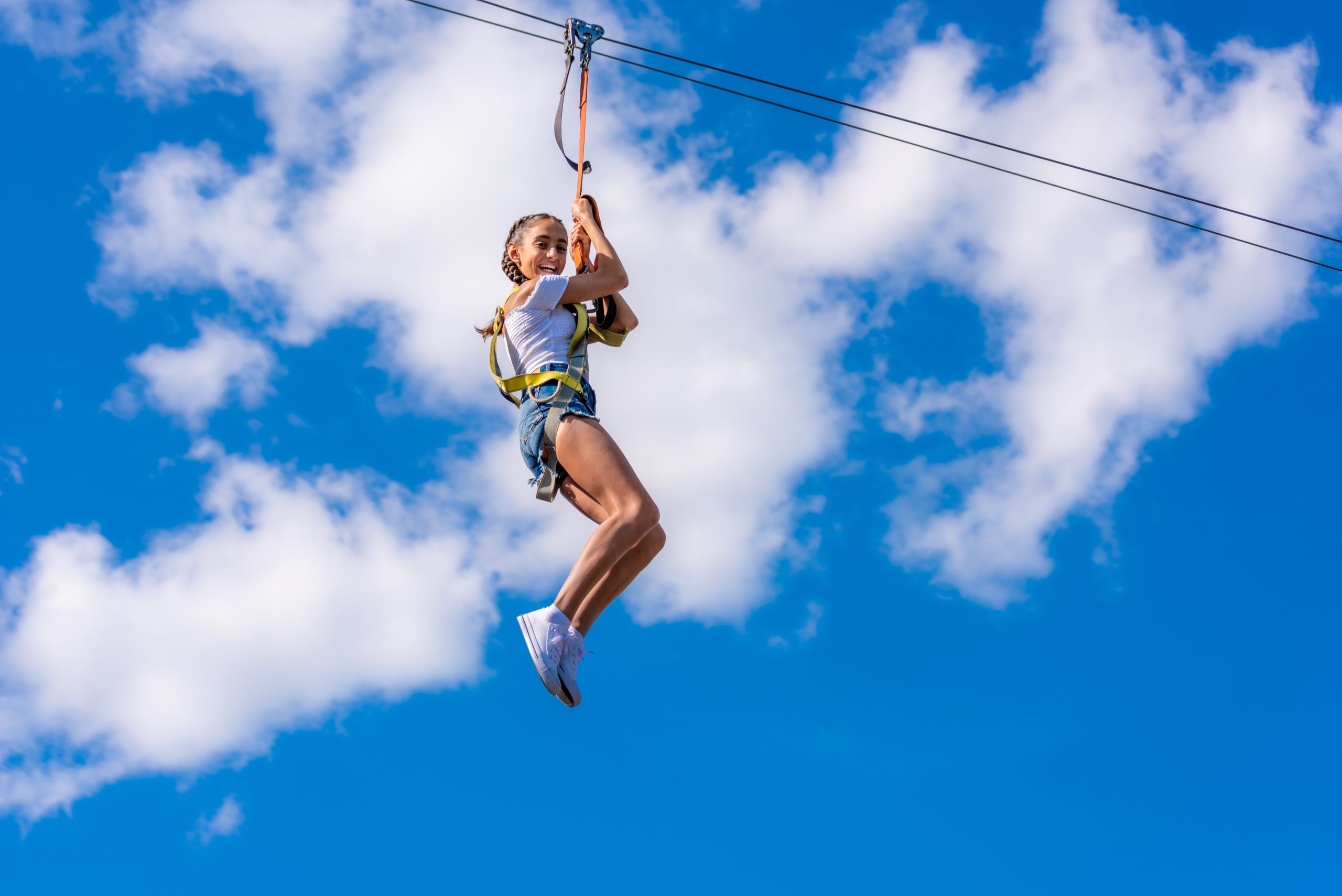 Young girl smiling on the Zip Line with the clouds in the background
