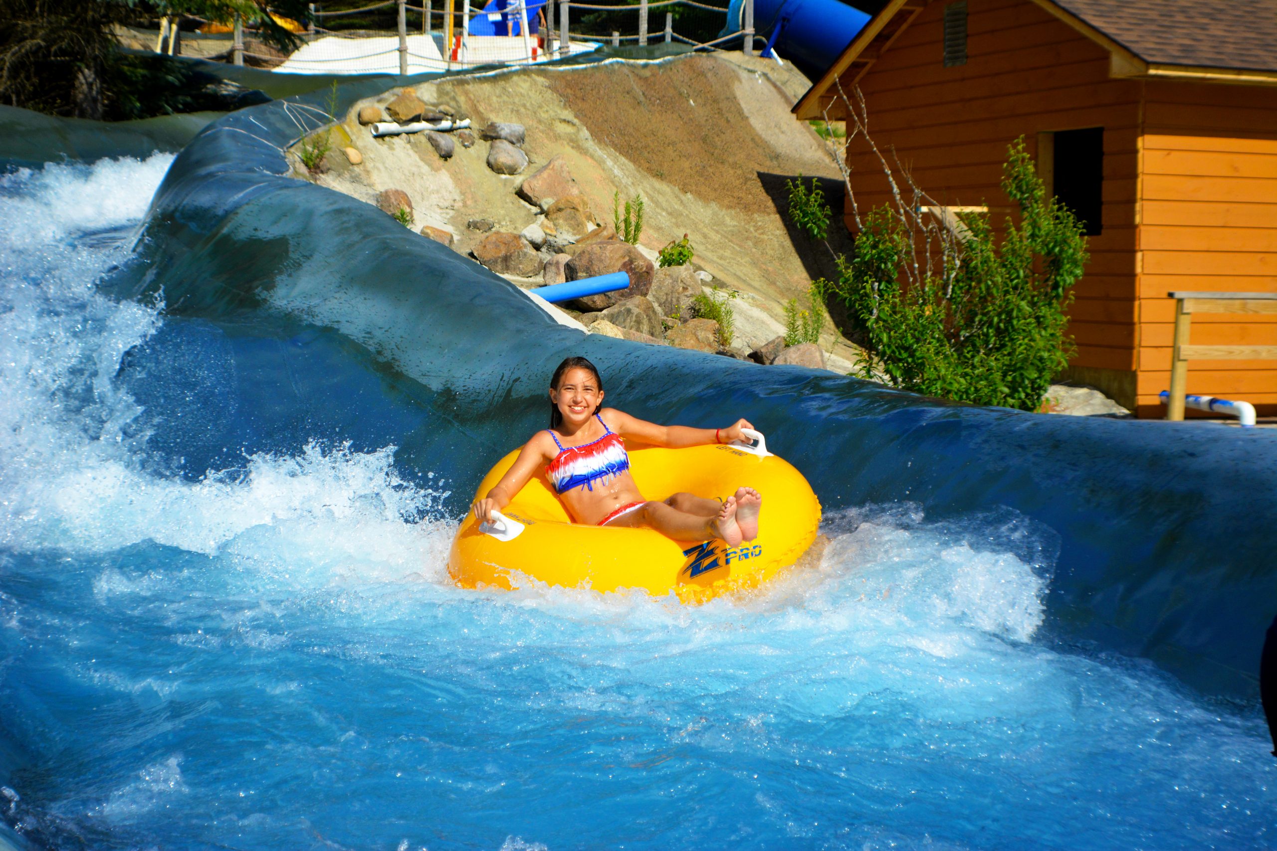 Photo of young girl going around a corner on the Raging Rapids smiling at the camera