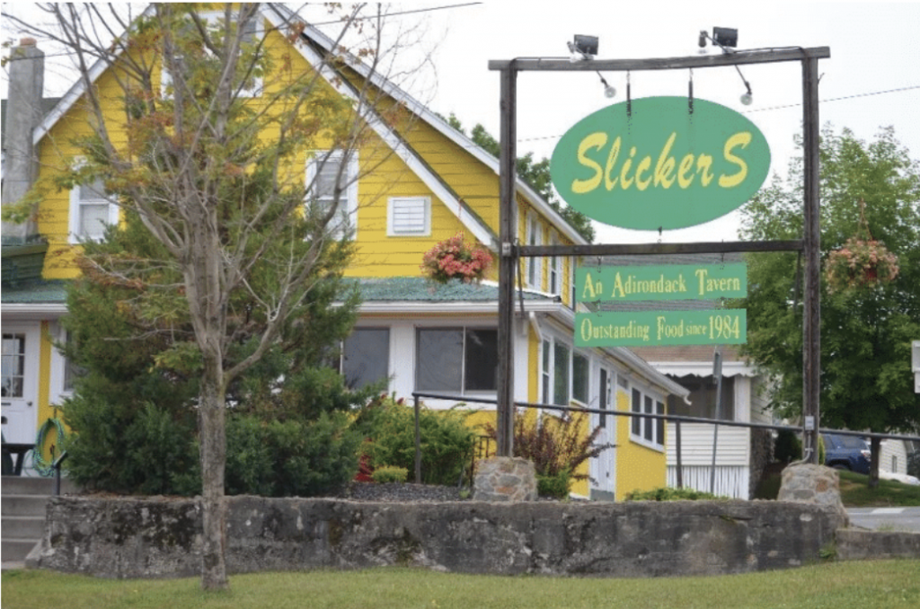 Picture taken outside a yellow building with a Slicker's sign outside 