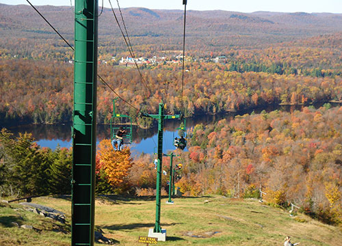 Chairlift view of a blue lake and fall foliage 