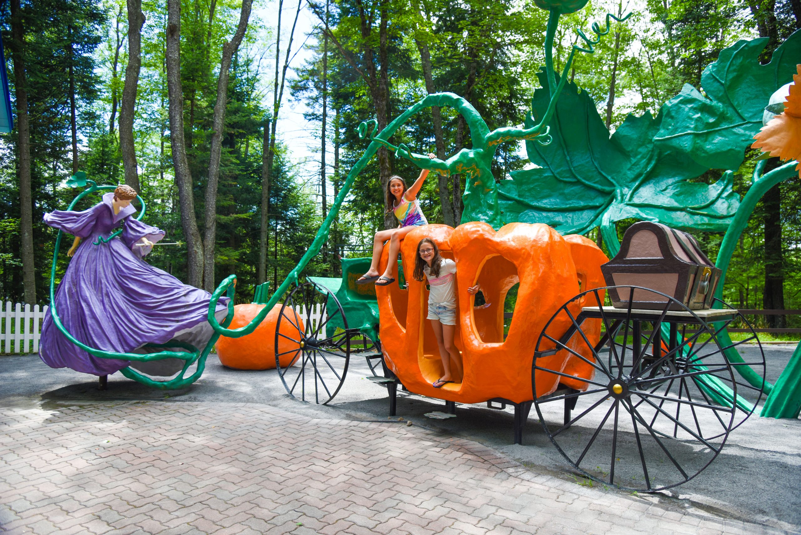 one of the fairy tales on storybook lane and two little girls standing on it smiling at the camera